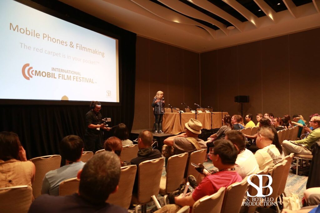 Susy Botello presents in room filled with attendees and large screen.